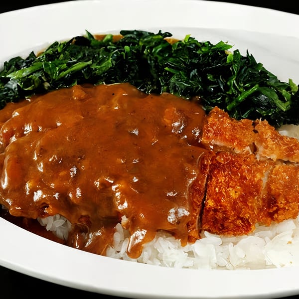 Nippon Curry's Japanese curry with crispy tonkatsu, white rice, and a side of green vegetables.