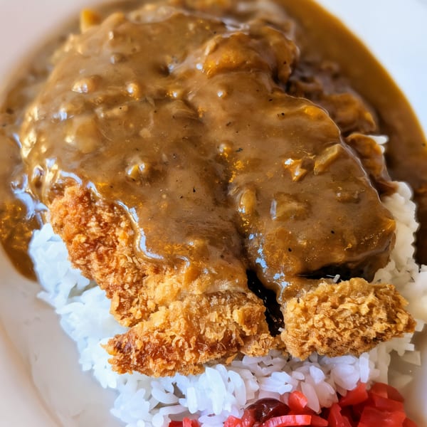 Close-up of Japanese curry with katsu over white rice and red pickled ginger.