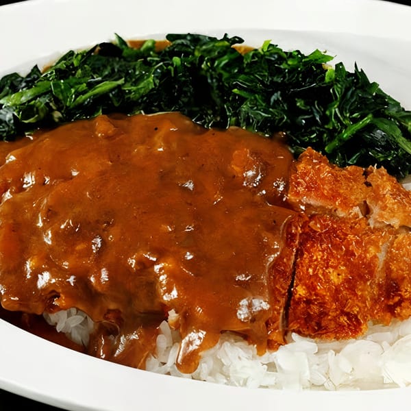 Japanese curry with crispy tonkatsu, rice, and a side of vibrant green vegetables.