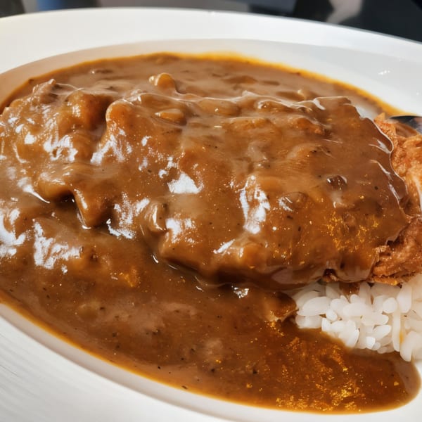Nippon Curry's Japanese curry with a crispy tonkatsu cutlet and white rice on a white plate.