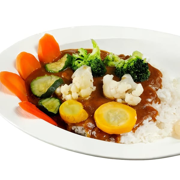 Japanese curry with rice, carrots, zucchini, broccoli, cauliflower, and yellow squash on a white plate.